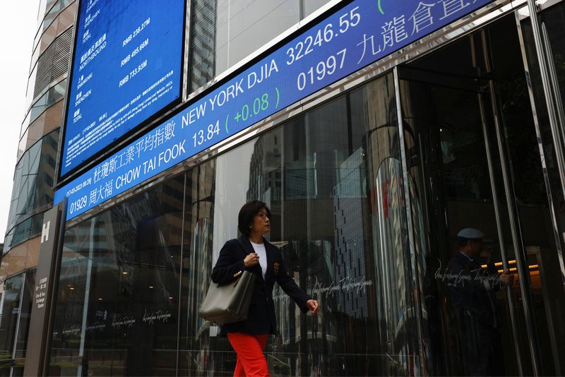 &copy; Reuters. A woman walks past a screen displaying the Hang Seng Index at Central district, in Hong Kong, China March 17, 2023. REUTERS/Tyrone Siu/ File Photo