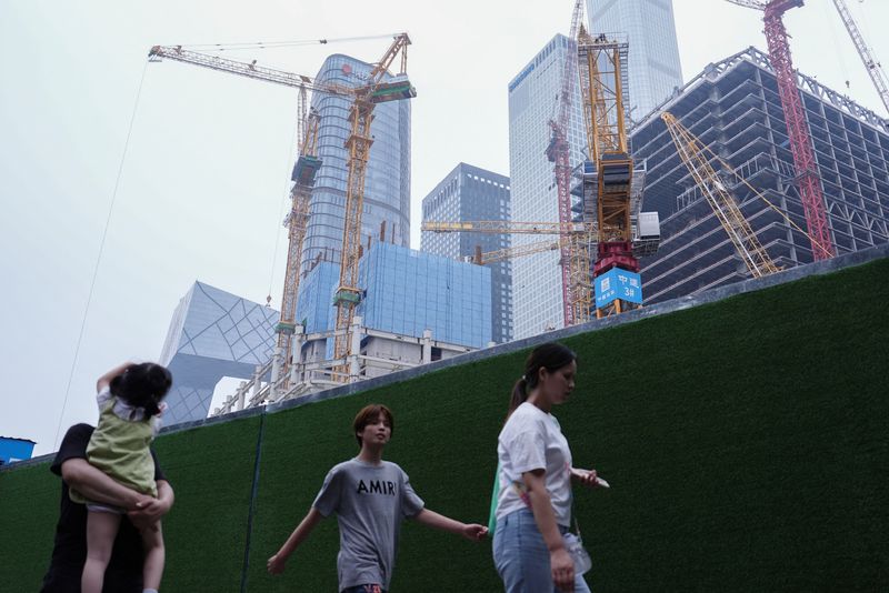 &copy; Reuters. People walk past a construction site in Beijing's Central Business District (CBD), China July 14, 2024. REUTERS/Tingshu Wang