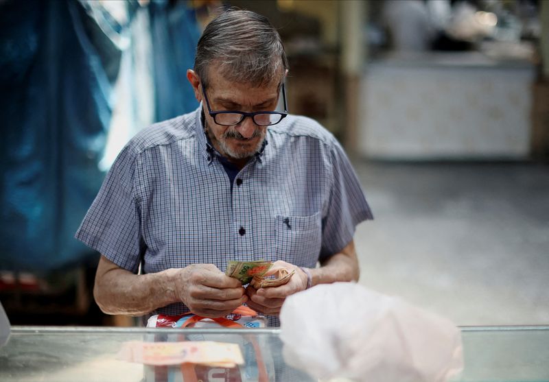 © Reuters. FILE PHOTO: A man counts peso bills to pay at a butcher's shop, as Argentina is battling with an annual inflation heading towards 200%, in Buenos Aires, Argentina January 5, 2024. REUTERS/Agustin Marcarian/File Photo