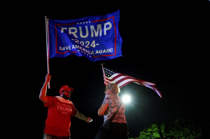 © Reuters. People hold flags after Republican presidential candidate and former U.S. President Donald Trump was injured when shots were fired during a campaign rally held in Butler, outside Trump's Mar-a-Lago resort in Palm Beach, Florida, U.S., July 13 , 2024. REUTERS/Marco Bello/File Photo