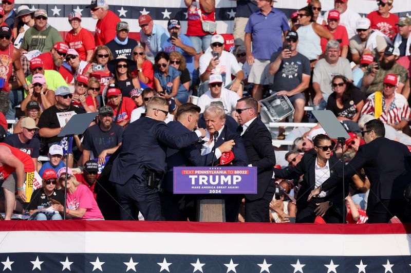 © Reuters. FILE PHOTO: Republican presidential candidate and former U.S. President Donald Trump is assisted by U.S. Secret Service personnel after he was shot in the right ear during a campaign rally at the Butler Farm Show in Butler, Pennsylvania, U.S., July 13, 2024. REUTERS/Brendan McDermi/File Photo