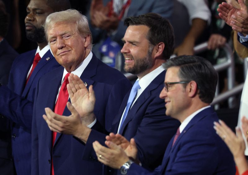 &copy; Reuters. Republican presidential nominee and former U.S. President Donald Trump looks on as Republican vice presidential nominee J.D. Vance, and House Speaker Mike Johnson applaud during Day 1 of the Republican National Convention (RNC), at the Fiserv Forum in Mil