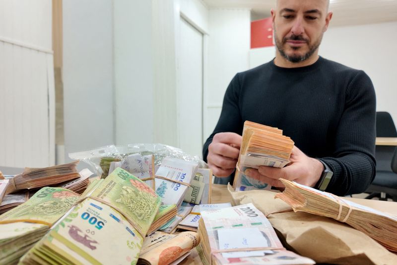 © Reuters. Juan Verzero, owner of Buenos Aires broker Succeso Propiedades counts money at his office in Buenos Aires, Argentina July 12, 2024. REUTERS/Noelle Harff