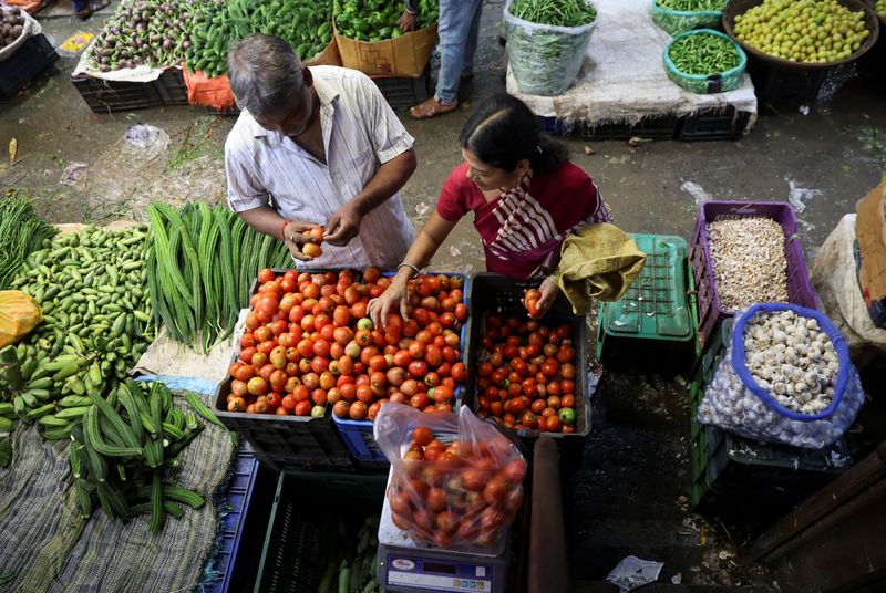 © Reuters. FILE PHOTO: A woman selects tomatoes from a vegetable vendor, at a wholesale market in Navi Mumbai, India August 4, 2023. REUTERS/Francis Mascarenhas/File Photo