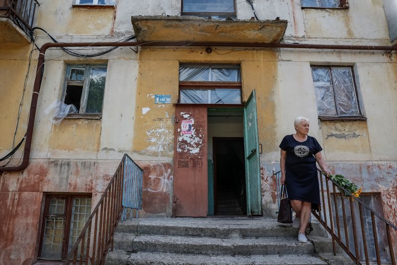 © Reuters. Iryna, 63, a local resident, who got help from the Insulate Ukraine charitable organisation after she faced the consequences of a Russian military attack in her area, is seen next to a residential building where she lives, amid Russia's attack on Ukraine, in the town of Mykolaivka, Donetsk region, Ukraine, June 18, 2024. REUTERS/Alina Smutko