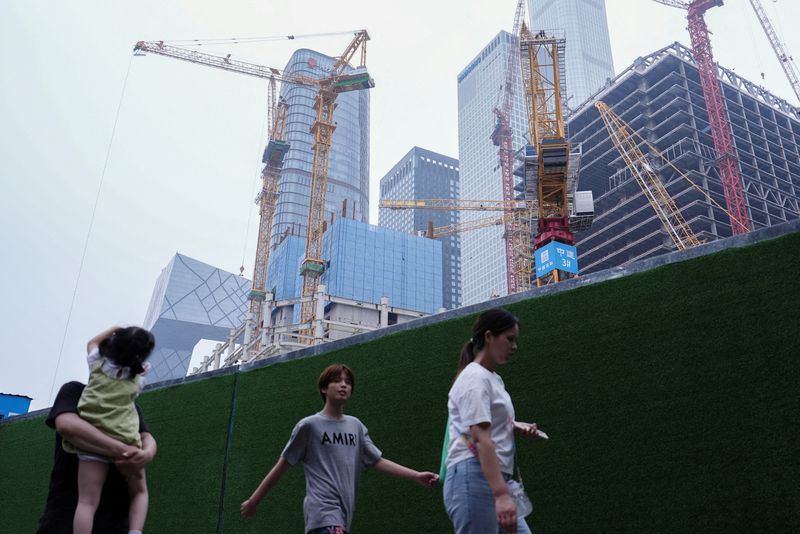 © Reuters. FILE PHOTO: People walk past a construction site in Beijing's Central Business District (CBD), China July 14, 2024. REUTERS/Tingshu Wang/File Photo