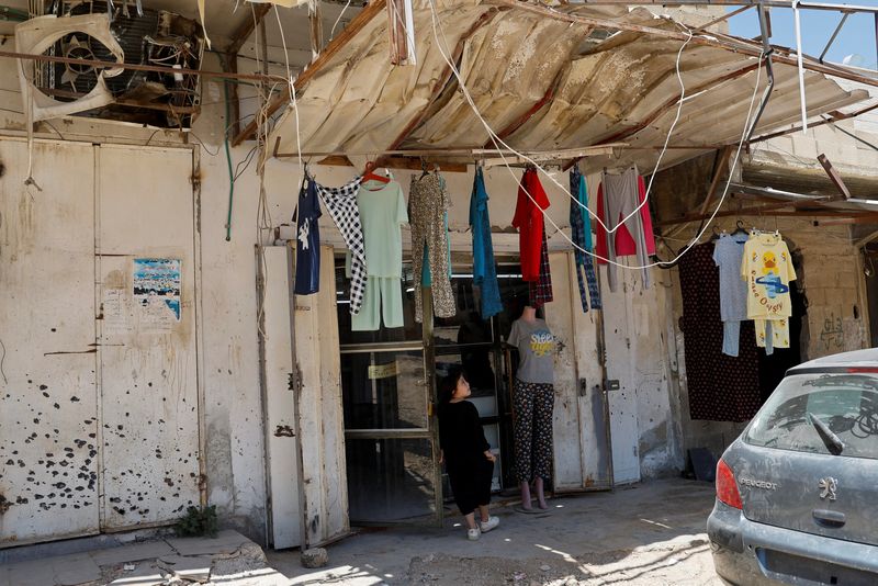 © Reuters. A Palestinian girl stands in front of a commercial store damaged by Israeli raid in Jenin camp in the Israeli-occupied West Bank, June 25, 2024. REUTERS/Raneen Sawafta/File Photo