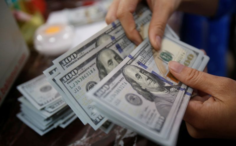 © Reuters. FILE PHOTO: A man counts US dollar notes at a bank. REUTERS/Kham/File Photo