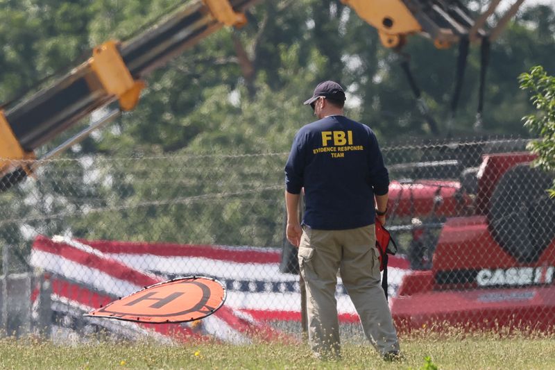 © Reuters. FILE PHOTO: A member of the FBI Evidence Response Team, works near the building where a gunman was shot dead by law enforcement, near the stage where Republican presidential candidate and former U.S. President Donald Trump survived an assassination attempt during a rally the day before, in Butler, Pennsylvania, U.S. July 15, 2024. REUTERS/Brendan McDermid/File Photo