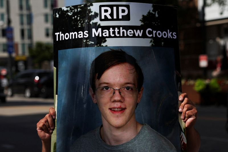 © Reuters. A man holds a sign with a picture of Thomas Crooks, following a shooting during a rally in which Republican presidential nominee and former U.S. President Donald Trump was injured, outside the Republican National Convention (RNC), in Milwaukee, Wisconsin, U.S., July 17, 2024. REUTERS/Shannon Stapleton