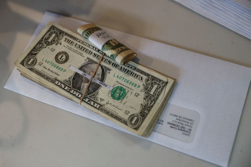 © Reuters. FILE PHOTO: U.S. dollar notes and a paycheck sits on a counter in Oakland, California, U.S. March 18, 2020. REUTERS/Shannon Stapleton/File Photo