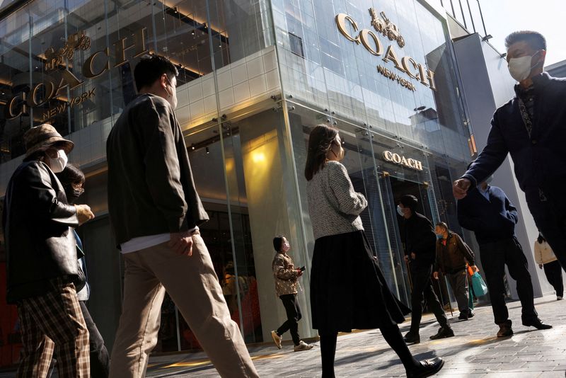 &copy; Reuters. FILE PHOTO: People walk past a store of the Coach luxury fashion retailer in a shopping district in Beijing, China, October 19, 2022. REUTERS/Thomas Peter/File Photo