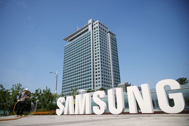 © Reuters. ẢNH TẬP TIN: Một công nhân đang tưới nước cho luống hoa bên cạnh logo của Samsung Electronics trong chuyến tham quan của giới truyền thông tại trụ sở chính của Samsung Electronics ở Suwon, Hàn Quốc, ngày 13 tháng 6 năm 2023. REUTERS/Kim Hong-Ji/Ảnh tập tin