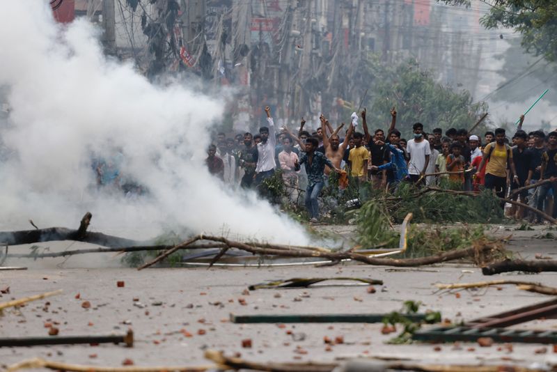 © Reuters. People gesture near smoke as protesters clash with Border Guard Bangladesh (BGB) and the police outside the state-owned Bangladesh Television as violence erupts across the country after anti-quota protests by students, in Dhaka, Bangladesh, July 19, 2024. REUTERS/Mohammad Ponir Hossain