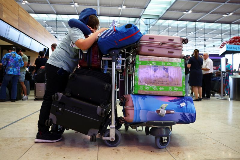 © Reuters. A person with luggage waits at BER airport following a global IT outage, in Berlin, Germany, July, 19, 2024. REUTERS/Nadja Wohlleben