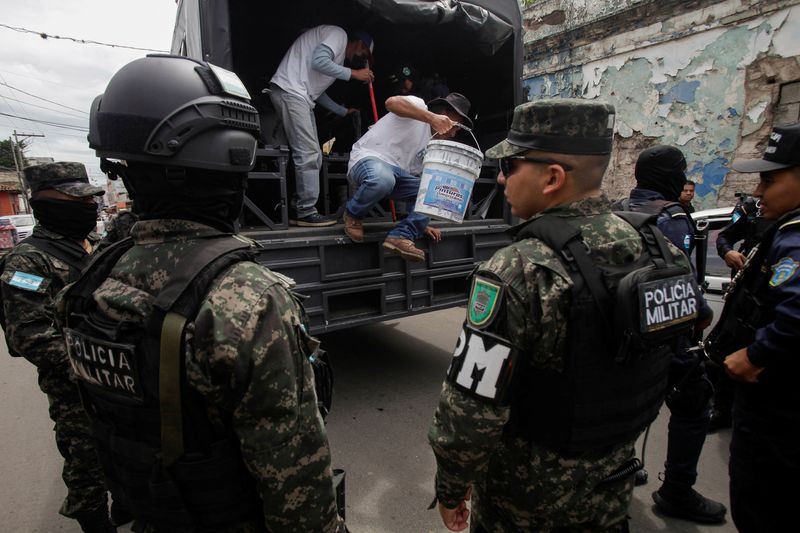 &copy; Reuters. Presos descem de ônibus militar com tintas e rolos enquanto policiais militares montam guarda, como parte de um programa governamental que visa promover a inserção social por meio do trabalho comunitário, em Tegucigalpan09/07/2024nREUTERS/Fredy Rodrig