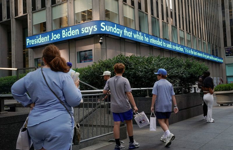 &copy; Reuters. People look at a news ticker, as news on U.S. President Joe Biden's announcement that he is dropping his reelection bid is displayed, in the Manhattan borough of New York City, U.S., July 21, 2024.  REUTERS/Eduardo Munoz