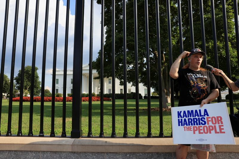 © Reuters. A person holds a placard as people gather outside the White House after U.S. President Joe Biden announced he is stopping his bid for reelection, in Washington, D.C., U.S., July 21, 2024. REUTERS/Kevin Mohatt