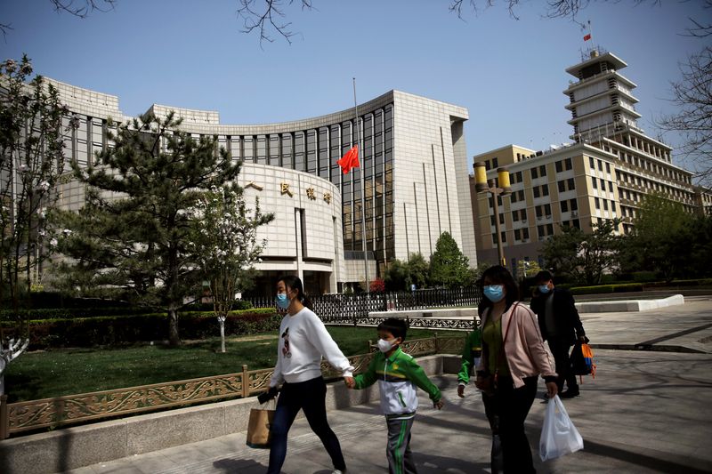 &copy; Reuters. People wearing face masks walk past the headquarters of Chinese central bank People's Bank of China (PBOC), where the Chinese national flag flies at half mast in Beijing as China holds a national mourning for those who died of the coronavirus disease (COV