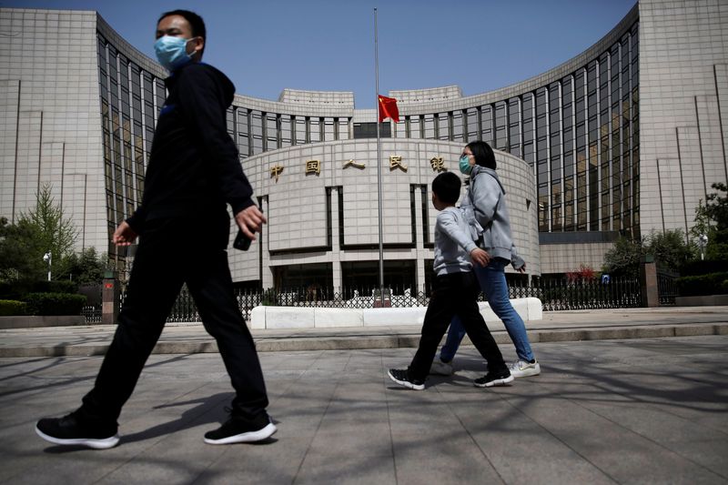 &copy; Reuters. FILE PHOTO: People wearing face masks walk past the headquarters of Chinese central bank People's Bank of China (PBOC), where the Chinese national flag flies at half mast in Beijing as China holds a national mourning for those who died of the coronavirus 