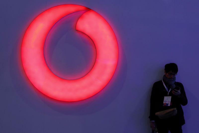 &copy; Reuters. FILE PHOTO: A man checks his mobile phone next to a Vodafone logo at the Mobile World Congress in Barcelona, Spain, February 28, 2018. REUTERS/Sergio Perez/File Photo