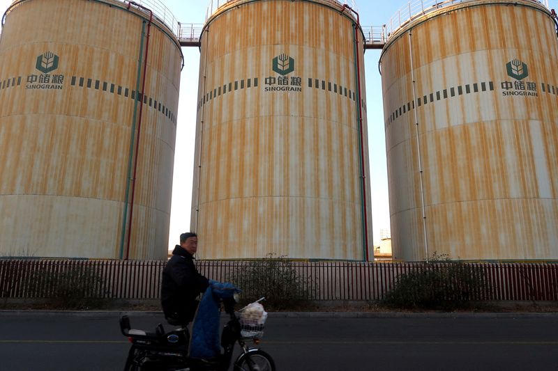 © Reuters. FILE PHOTO: A man cycles past storage facilities of China's state grain stockpiler Sinograin near Tianjin port, China December 12, 2019. REUTERS/Yilei Sun/File Photo