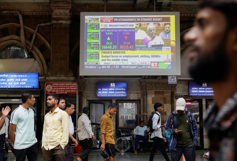 © Reuters. People walk past a screen displaying India's Finance Minister Nirmala Sitharaman's budget speech at a railway station in Mumbai, India, July 23, 2024. REUTERS/Francis Mascarenhas