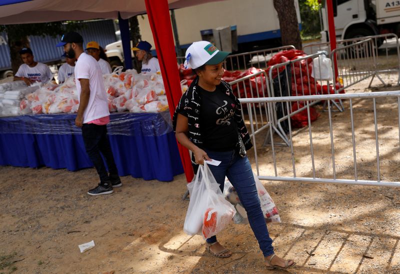 &copy; Reuters. A woman smiles as she walks with her shopping of food reduced in price and offered to low-income citizens as part of Venezuela's President Nicolas Maduro's presidential campaign, while he seeks reelection for a third term in the upcoming election on July 