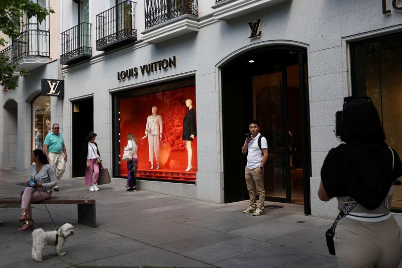 © Reuters. FILE PHOTO: People stand next to a Louis Vuitton store in the downtown district of Salamanca, in Madrid, Spain, May 18, 2024. REUTERS/Violeta Santos Moura/File Photo