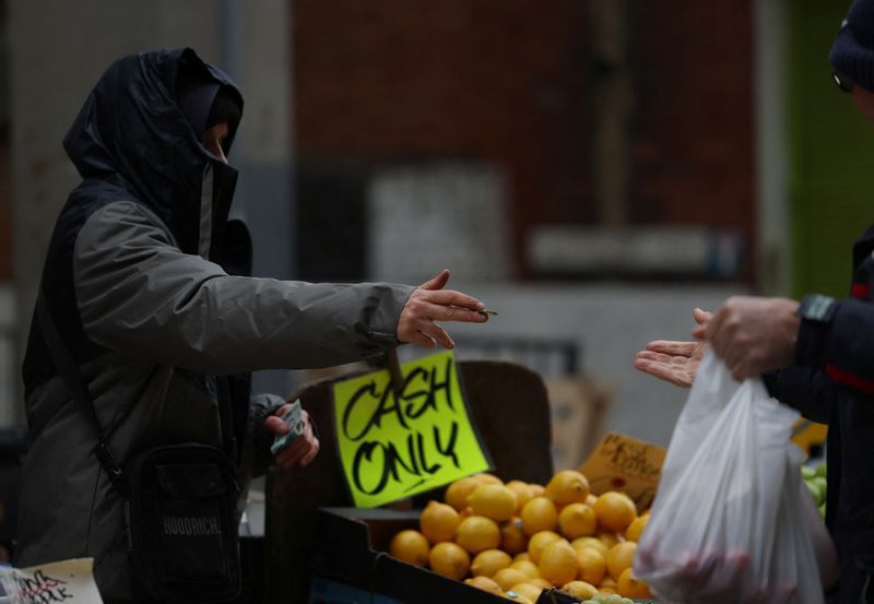 © Reuters. FILE PHOTO: A worker returns cash to a customer after buying produce from a stall on Surrey Street market in Croydon, south London, Britain, February 26, 2024. REUTERS/Hannah McKay/File Photo