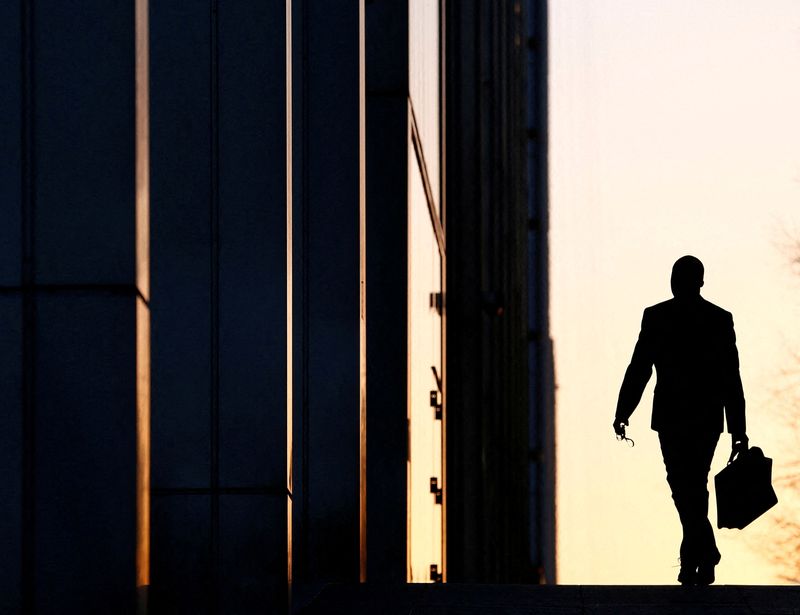 © Reuters. FILE PHOTO:  A worker arrives at his office in the Canary Wharf business district in London Feb. 26, 2014./File Photo/File Photo