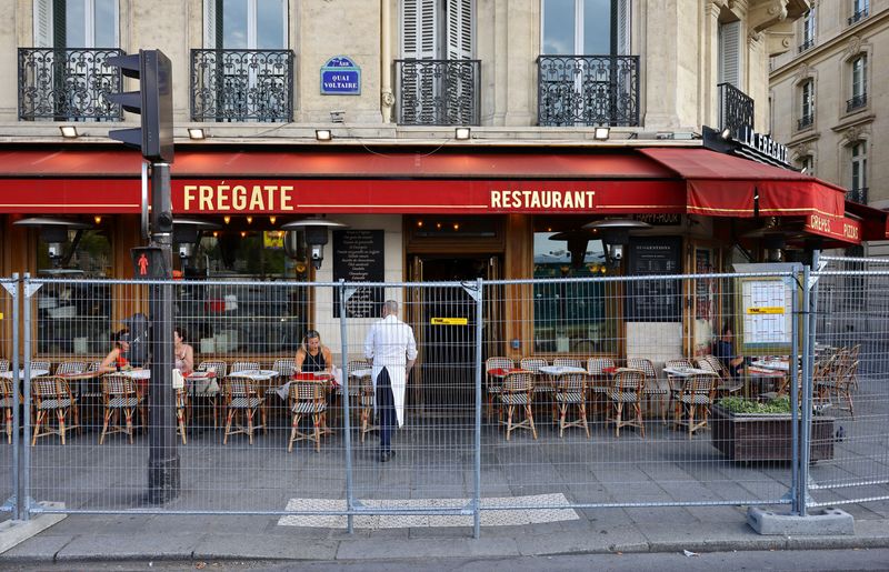 © Reuters. FILE PHOTO: People sit at a restaurant as the security perimeter fence for the opening ceremony is deployed ahead of the Paris 2024 Olympics and Paralympics Games in Paris, France, July 19, 2024.   REUTERS/Fabrizio Bensch/File photo