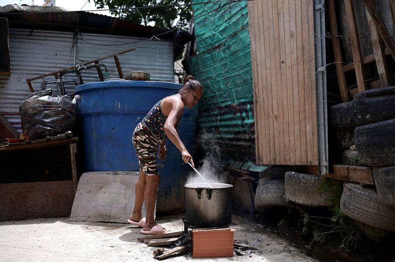 &copy; Reuters. Mulher cozinha em fogão a lenha improvisado Caracas, na Venezuelan21/07/2024nREUTERS/Gaby Oraa