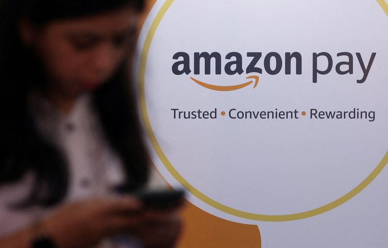 &copy; Reuters. FILE PHOTO: A woman uses her phone next to a logo of the Amazon Pay logo during Global Fintech Fest in Mumbai, India September 20, 2022. REUTERS/Francis Mascarenhas/File Photo