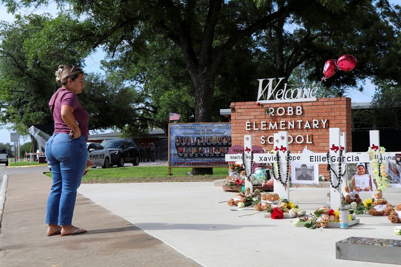 © Reuters. FILE PHOTO: A woman brings flowers to a memorial for the victims of a school shooting at Robb Elementary School, one year after the shooting, in Uvalde, Texas, U.S., May 24, 2023. REUTERS/Evan Garcia/File Photo