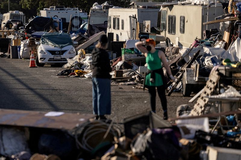 &copy; Reuters. FILE PHOTO: Volunteers help to clean up belongings at an encampment of homeless people near the Nimitz Freeway in Oakland after the city issued an order to remove and clean up the area where between 30 to 40 people live in cars, RVS, tents, and other make