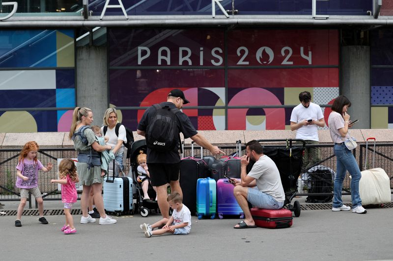 © Reuters. Travellers from Sydney, Australia, wait outside the Gare Montparnasse train station as they try to search for other trains after their trip was affected when vandals targeted France's high-speed train network with a series of coordinated actions that brought major disruption, ahead of the Paris 2024 Olympics opening ceremony, in Paris, France, July 26, 2024. REUTERS/Maye-E Wong    