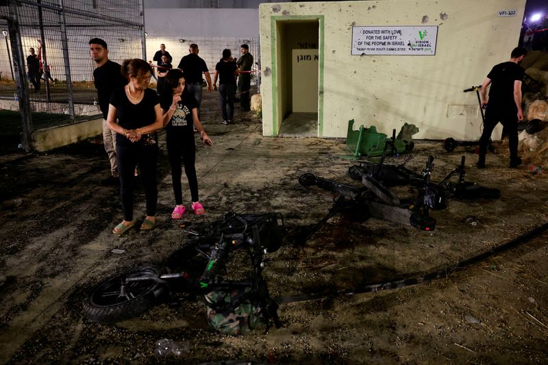 © Reuters. FILE PHOTO: People look at the damage after rockets were launched across Lebanon's border with Israel which, according to Israel's ambulance services killed people, at a soccer pitch in Majdal Shams, a Druze village in the Israeli-occupied Golan Heights, July 27, 2024. REUTERS/Ammar Awad/File Photo