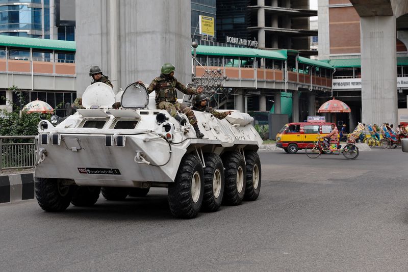 © Reuters. FILE PHOTO: Members of Bangladesh Army gesture as they patrol in an armoured vehicle on the second-day of curfew, as violence erupted in parts of the country after protests by students against government job quotas, in Dhaka, Bangladesh, July 21, 2024. REUTERS/Mohammad Ponir Hossain/File Photo