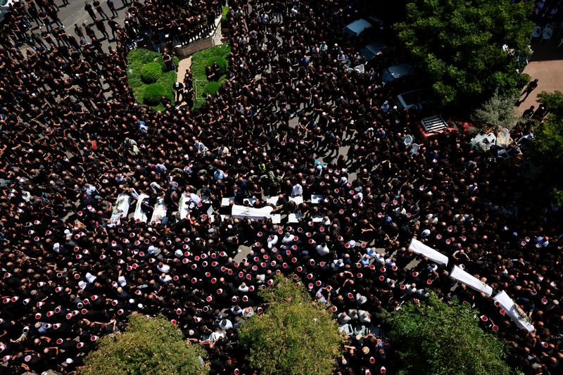 © Reuters. Mourners carry coffins, during the funeral of children who were killed at a soccer pitch by a rocket fired from Lebanon, in Majdal Shams, a Druze village in the Israeli-occupied Golan Heights, July 28, 2024. REUTERS/Ammar Awad