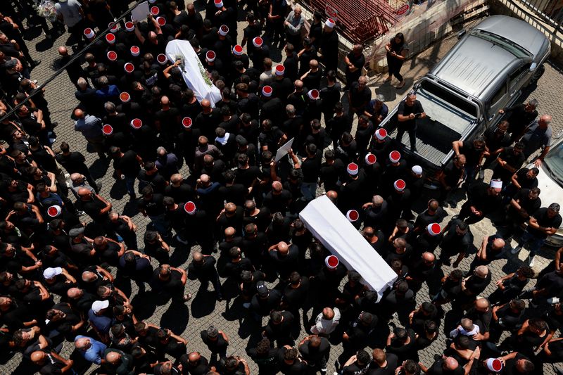 &copy; Reuters. Mourners carry coffins, during the funeral of children who were killed at a soccer pitch by a rocket Israel says was fired from Lebanon, in Majdal Shams, a Druze village in the Israeli-occupied Golan Heights, July 28, 2024. REUTERS/Ammar Awad