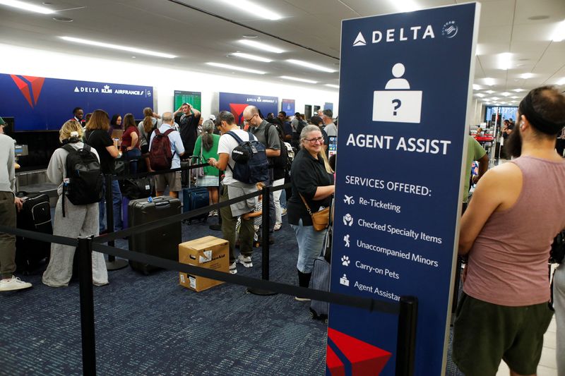 &copy; Reuters. FILE PHOTO: Airline passengers wait in line at the Delta, KLM, and Air France ticketing counters after flights were grounded worldwide due to a tech outage caused by an update to CrowdStrike's "Falcon Sensor" software which crashed Microsoft Windows syste