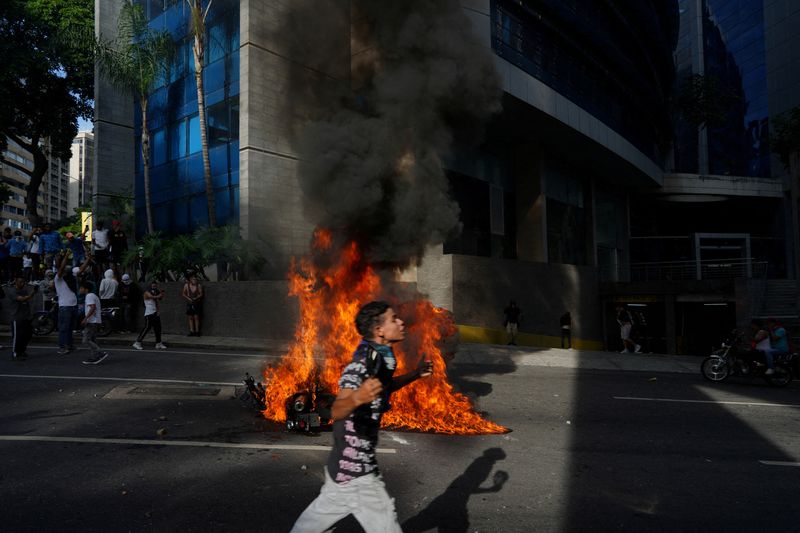 © Reuters. A police motorbike burns as people protest following the announcement by the National Electoral Council that Venezuela's President Nicolas Maduro won the presidential election, in Caracas, Venezuela July 29, 2024. REUTERS/Alexandre Meneghini  