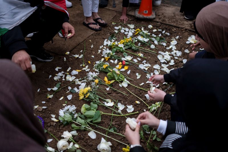 © Reuters. FILE PHOTO: Mourners place flowers at the grave of Wadea Al-Fayoume at Parkholm Cemetery where the burial took place of Wadea Al-Fayoume, 6, a Muslim boy who according to police was stabbed to death in an attack that targeted him and his mother for their religion and as a response to the war between Israel and Hamas, in LaGrange, Illinois, U.S. October 16, 2023.  REUTERS/Jim Vondruska/File Photo