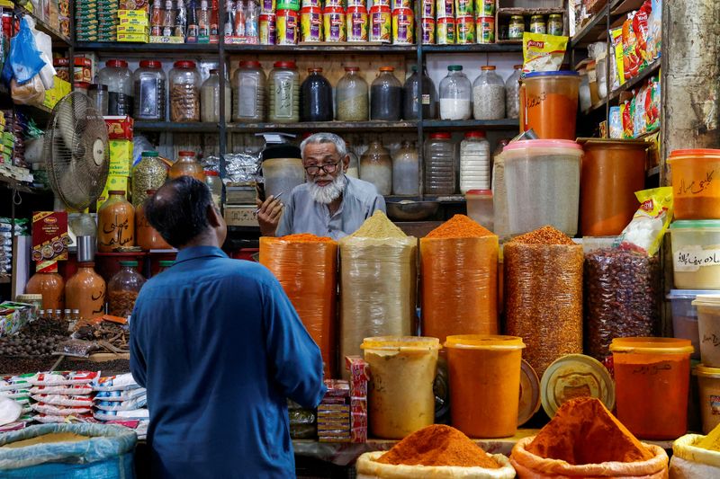 © Reuters. FILE PHOTO: A shopkeeper speaks with a customer while selling spices at a market in Karachi, Pakistan June 11, 2024. REUTERS/Akhtar Soomro/File Photo