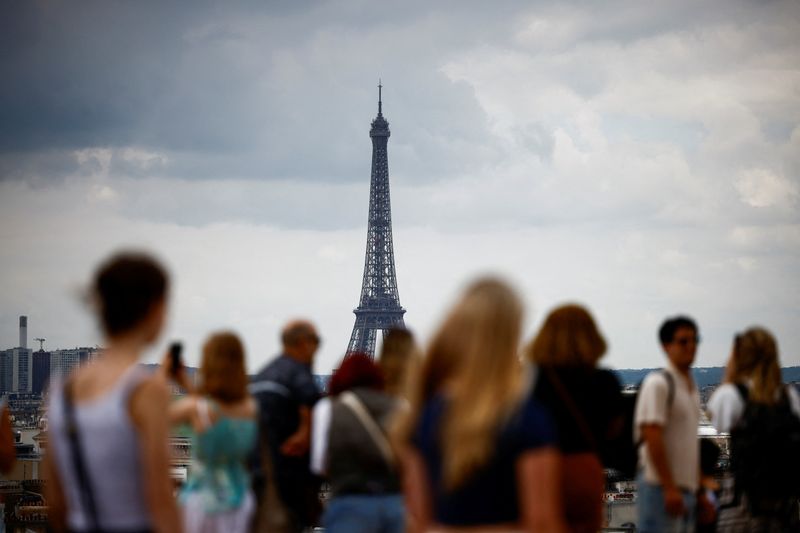 © Reuters. Tourists look at the Eiffel Tower and the Paris skyline from the rooftop of the Galeries Lafayette department store on a cloudy day in Paris, France, July 1, 2024. REUTERS/Yara Nardi/ File Photo