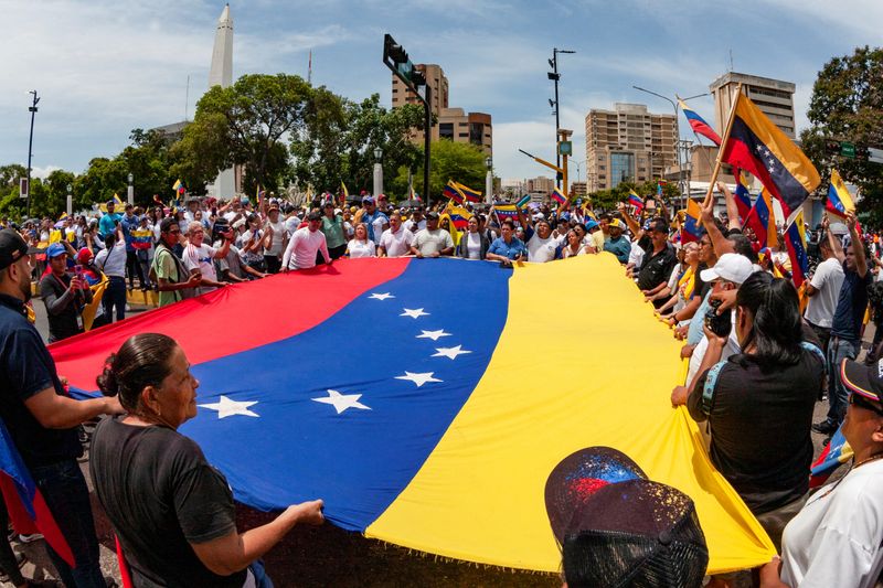 © Reuters. People carry Venezuela's national flag to protest the election results that awarded Venezuela's President Nicolas Maduro with a third term, in Maracaibo, Venezuela July 30, 2024. REUTERS/Isaac Urrutia