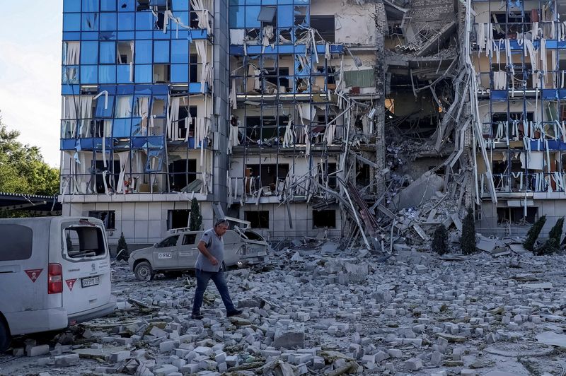 © Reuters. FILE PHOTO: A man walks next to an office building of FSD (Fondation Suisse de Déminage), a non-governmental humanitarian organisation, damaged during a Russian missile attack, amid Russia's attack on Ukraine, in Kharkiv, Ukraine July 24, 2024. REUTERS/Vyacheslav Madiyevskyy/File Photo