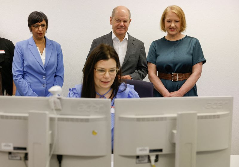 © Reuters. FILE PHOTO: German Chancellor Olaf Scholz, German Minister for Family Affairs, Senior Citizens, Women and Youth Lisa Paus and the chairwoman of the Family Center Vanessa Ahuja watch team leader Ioana Ullrich working on her computer during their visit at the Family benefit Center of Berlin-Brandenburg on June 19, 2023, in Potsdam. ODD ANDERSEN/Pool via REUTERS/File Photo