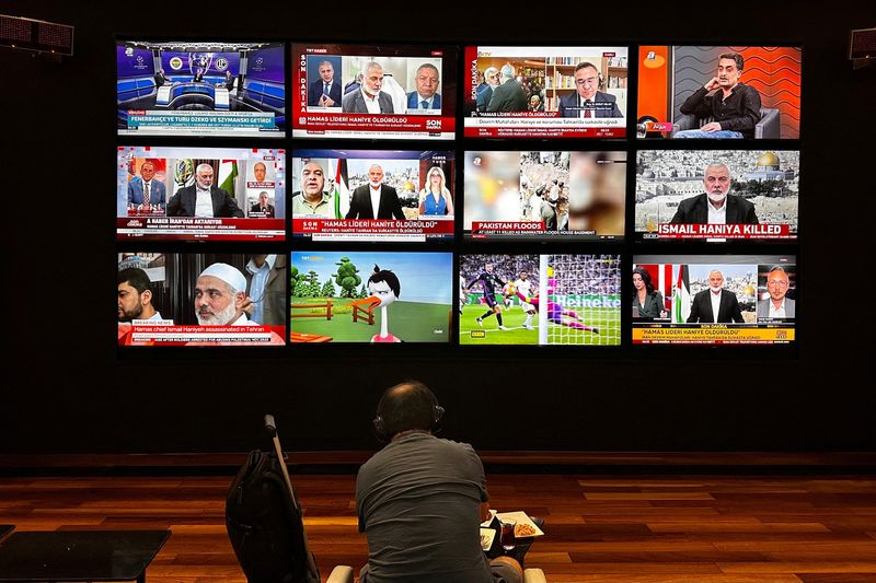 © Reuters. A person watches the news on multiple TV screens, most of them announcing the killing of senior Hamas leader Ismail Haniyeh, in Istanbul, Turkey, July 31, 2024. REUTERS/Alkis Konstantinidis/ File Photo